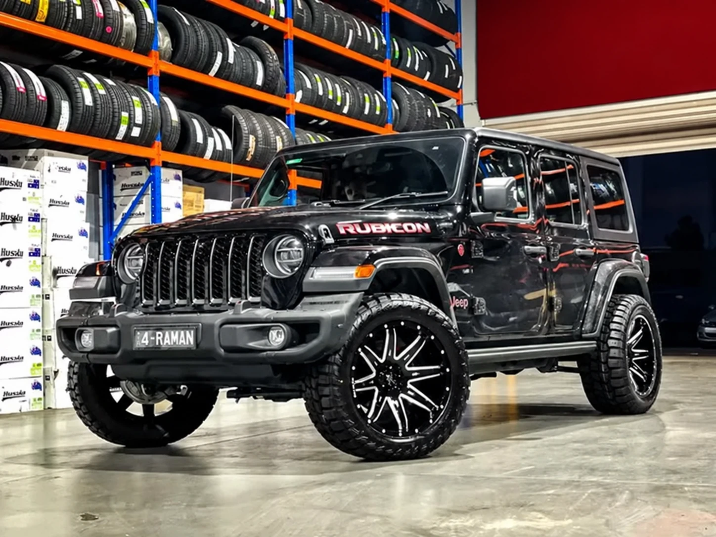 Black Jeep with dark alloy wheels and a maroon-red wall in the workshop