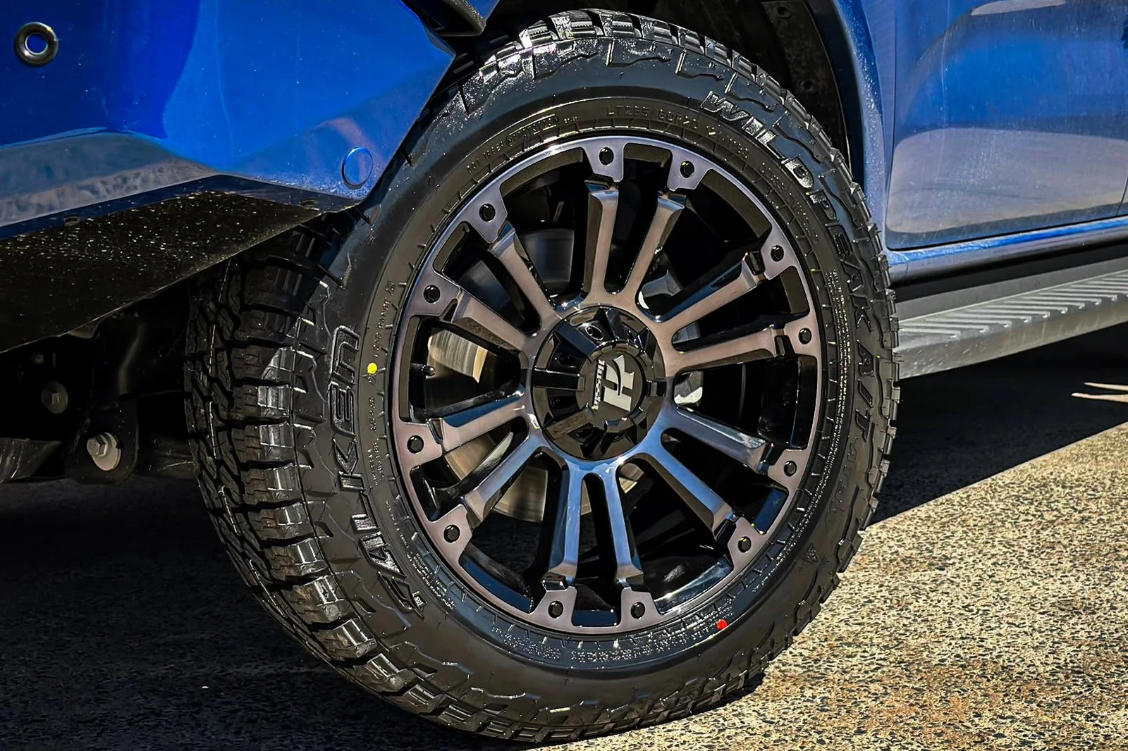 Black and machined alloy wheel fitted to a blue vehicle