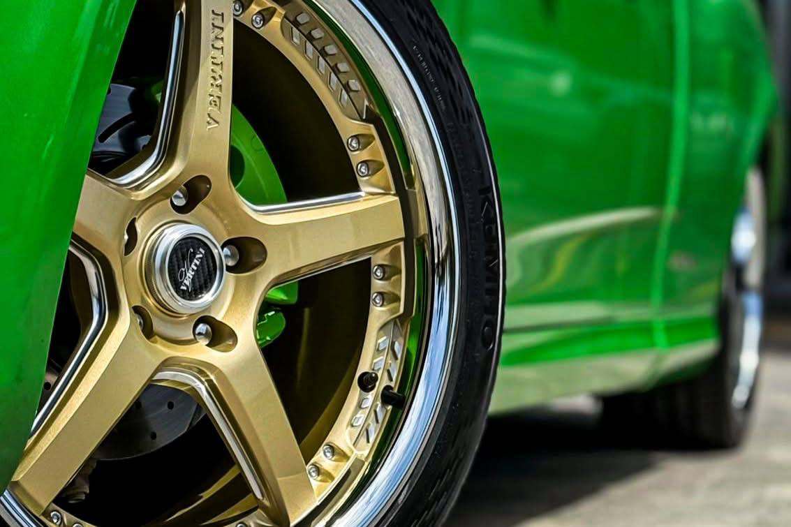 Gold alloy wheel with a polished lip and green brake calliper