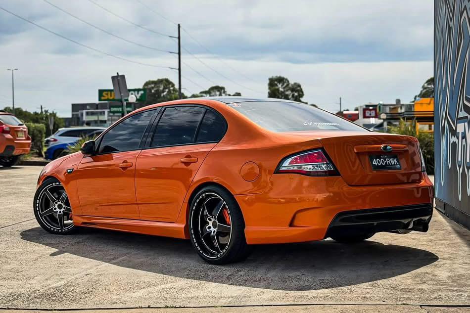 Orange Ford sedan with black-and-machined alloy wheels