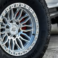 A polished multi-spoke wheel with a chunky tyre and red brake calliper