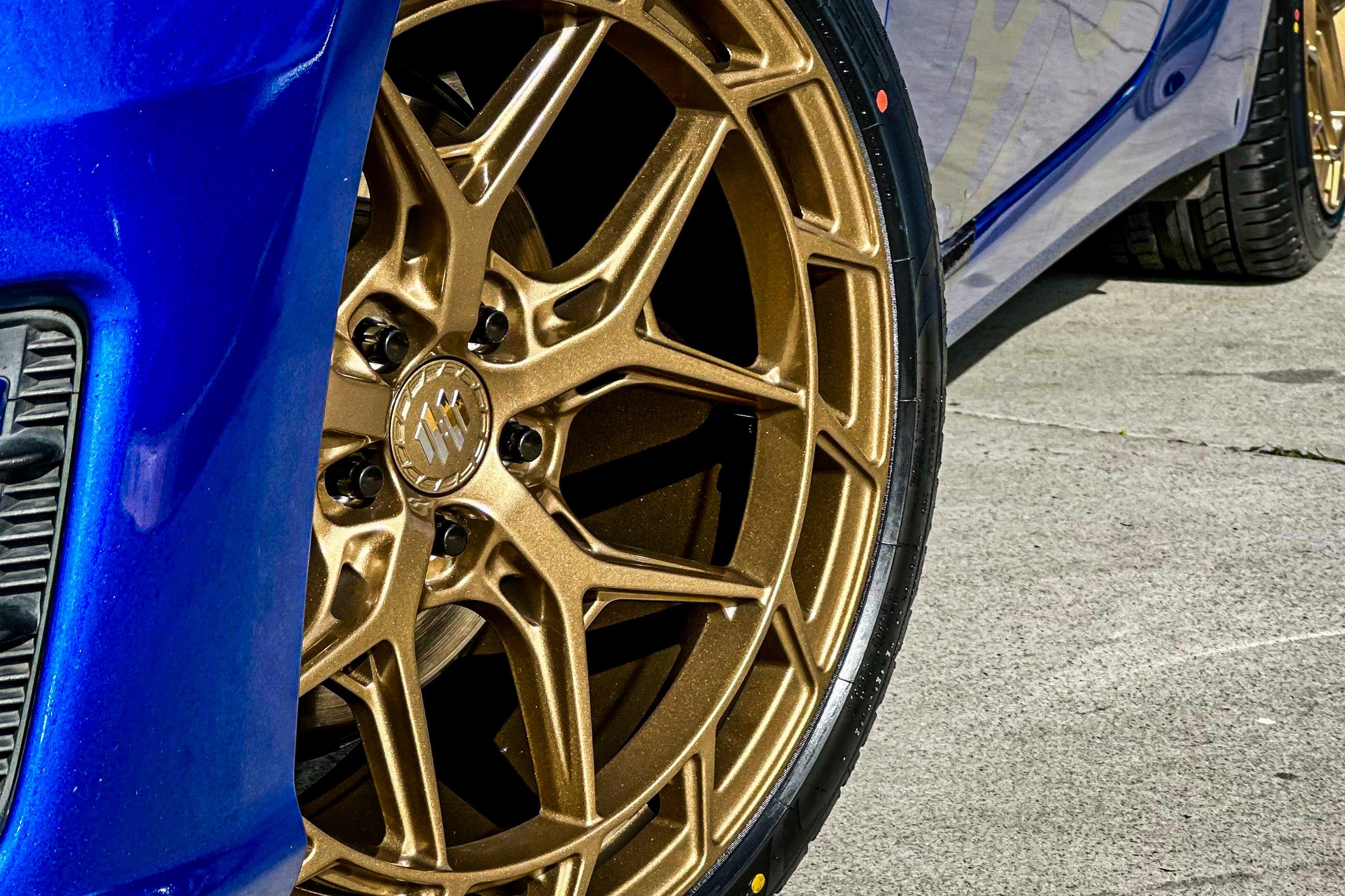 A bronze multi-spoke Hussla wheel and tyre on a blue Subaru BRZ