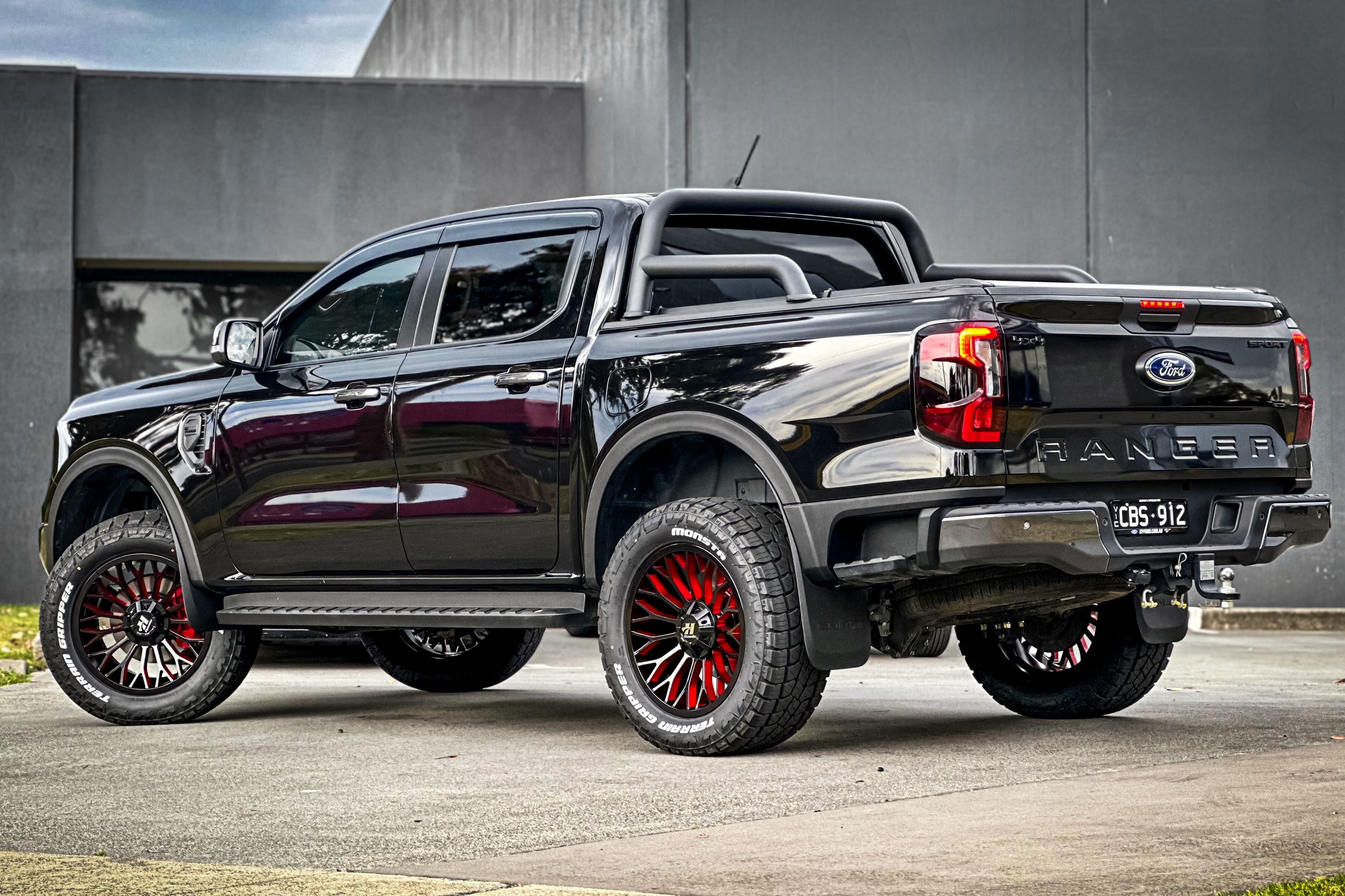 A black Ford Ranger with dark multi-spoke wheels and red detailing