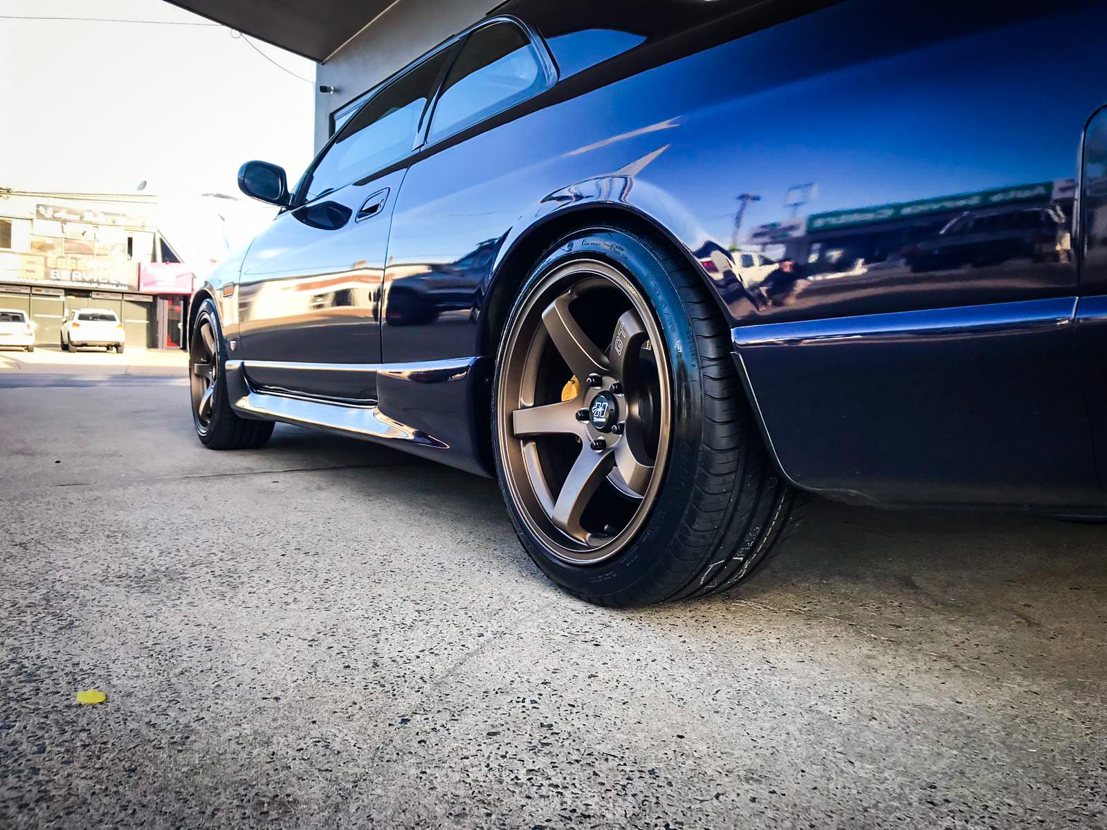 A dark blue Nissan Skyline with a five-spoke alloy wheel and yellow brake calliper